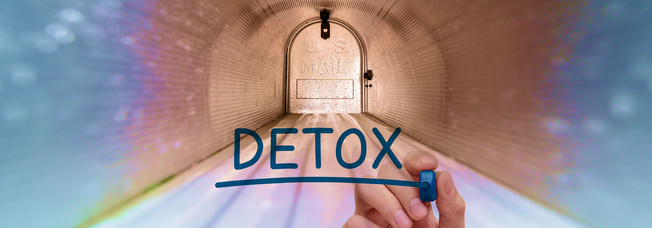 Image showing a hand drawing the word 'DETOX' with a blue marker in front of a blurred background featuring a tunnel-like mailbox, indicating the concept of an inbox detox.